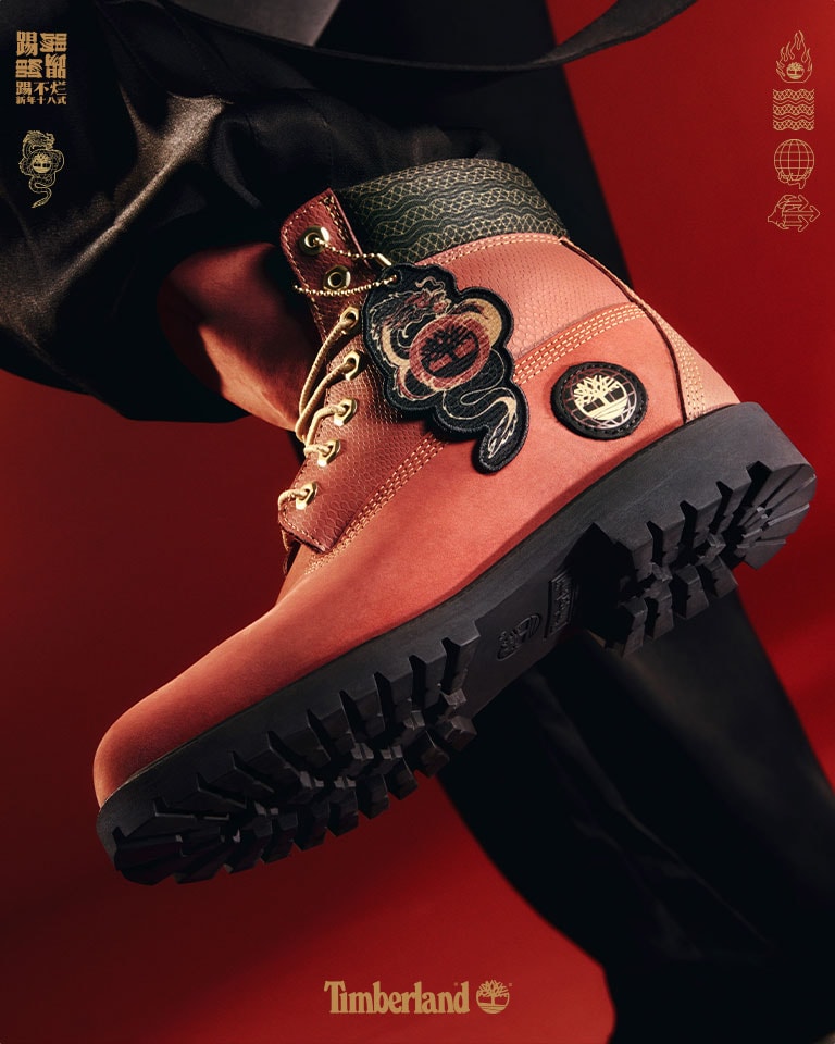 Image shows a bright, dark red background which features a closeup of a Timberland 6-inch boot in bold red leather with gold accents and gold dragon hangtags. Faint gold Chinese characters are visible in the center of the image.